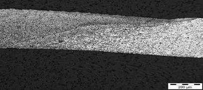 Figure7: Butt weld of 300&mu;m thick sheets of aluminium alloy - Cross section showing transition from weld metal (left) to parent metal (right)